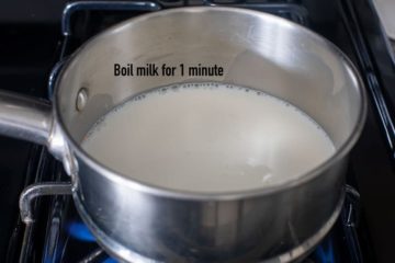 angle view of a stainless steel pan with milk being heated on a burner