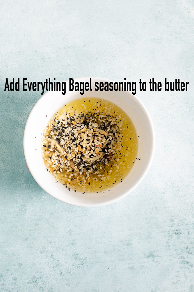 top view of a white bowl with melted butter and everything bagel seasoning