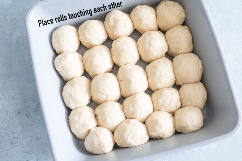 Top view of 25 dinner roll balls in a 10.24" grey square baking dish