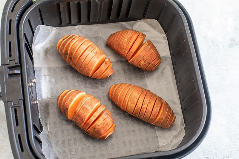 Top view of cut hasselback sweet potatoes in the air fryer basket