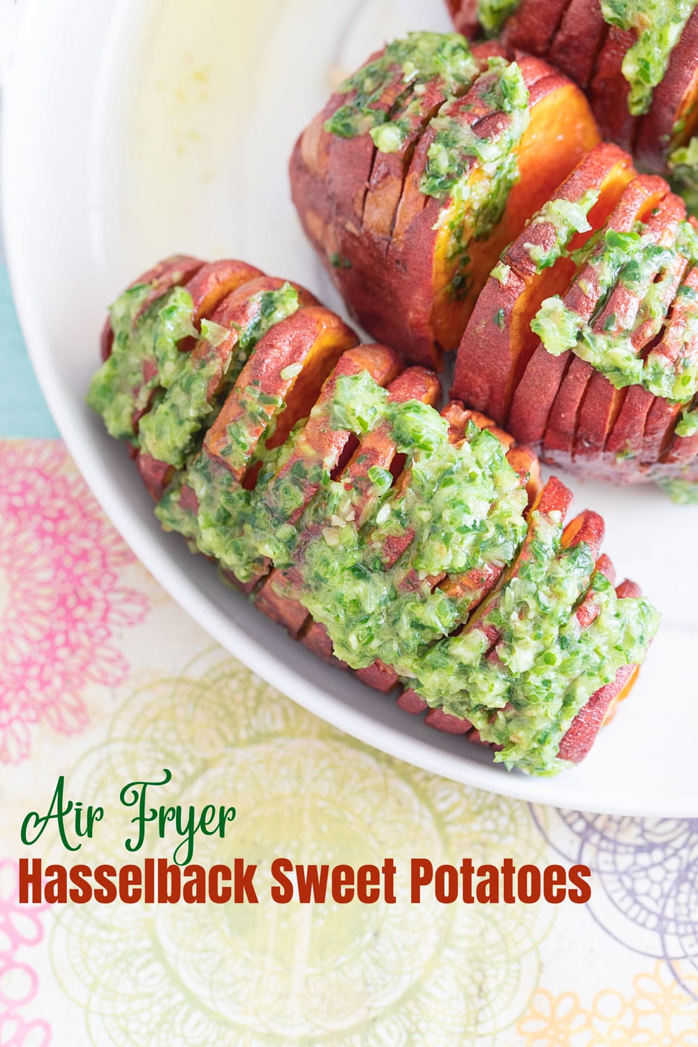 Top and closeup view of one hasselback sweet potato on a white plate. It has a scallion pesto topping