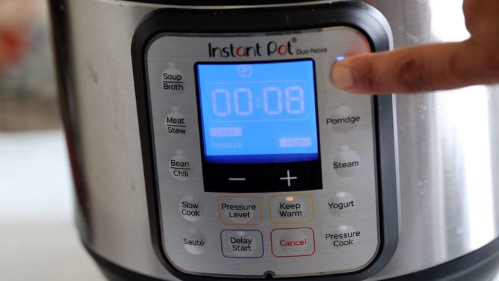 The author pressing the "Rice" button on the instant pot and it's displaying 8 minutes.