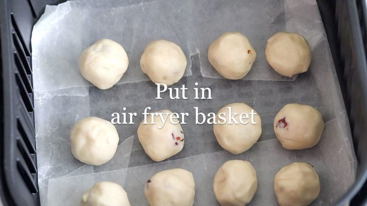 top view of 12 snowballs lined in a wax paper inside the air fryer basket