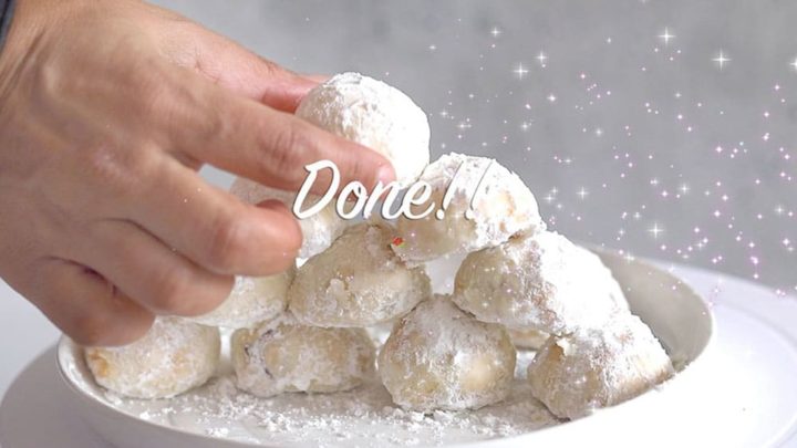Top view of the author putting the last air fryer snowball on top of a pyramid of snowball cookies