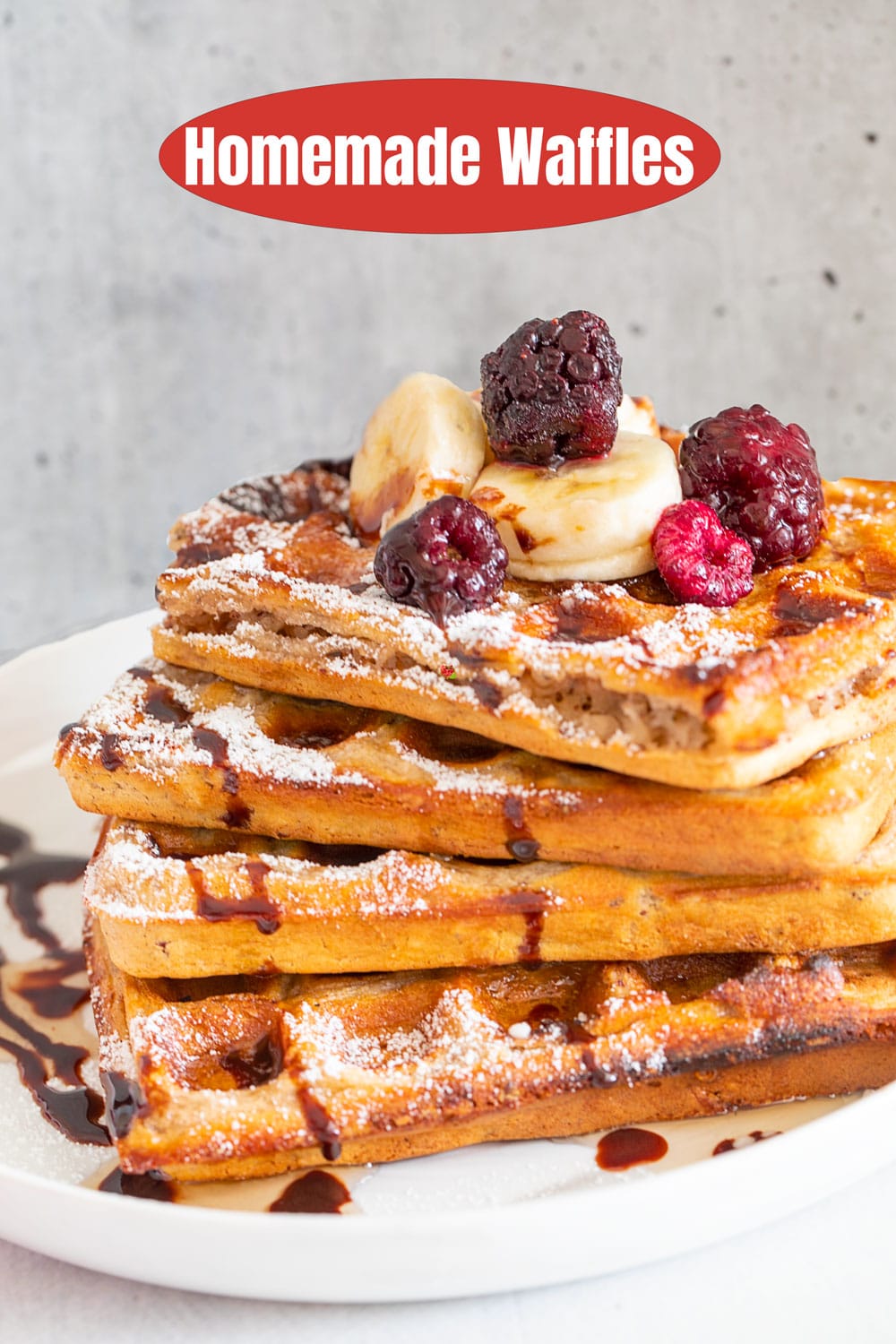 Front view of 4 waffles stack topped with chocolate sauce, maple syrup, bananas and berries