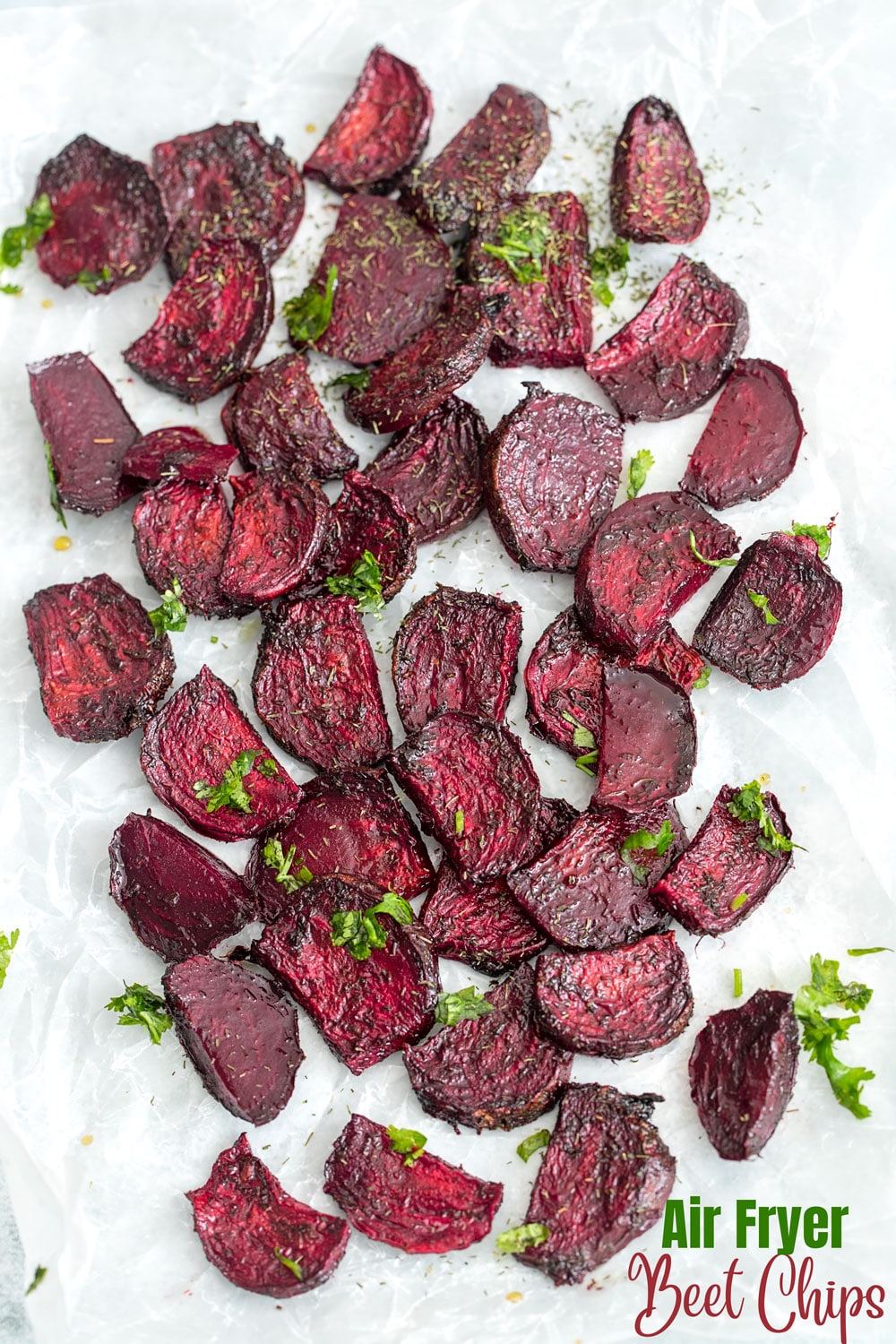 Top view of air fryer beet chips on a white wax paper with cilantro garnish