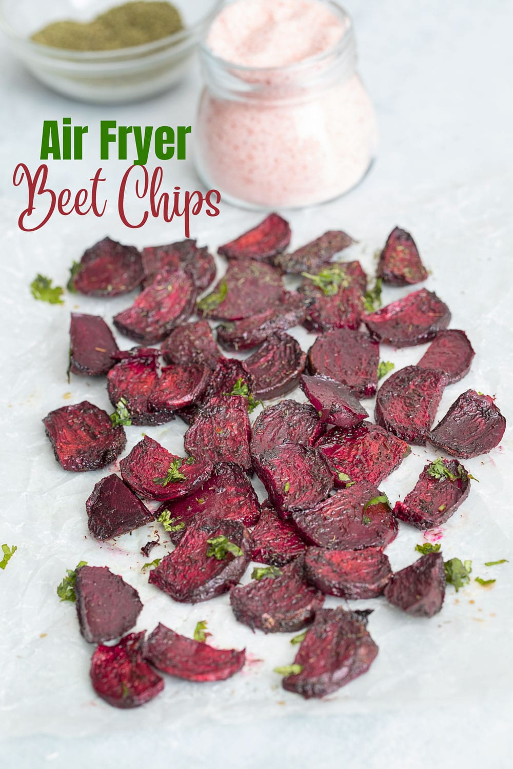 Angle view of beet chips with salt bottle and dill seasoning in a bowl