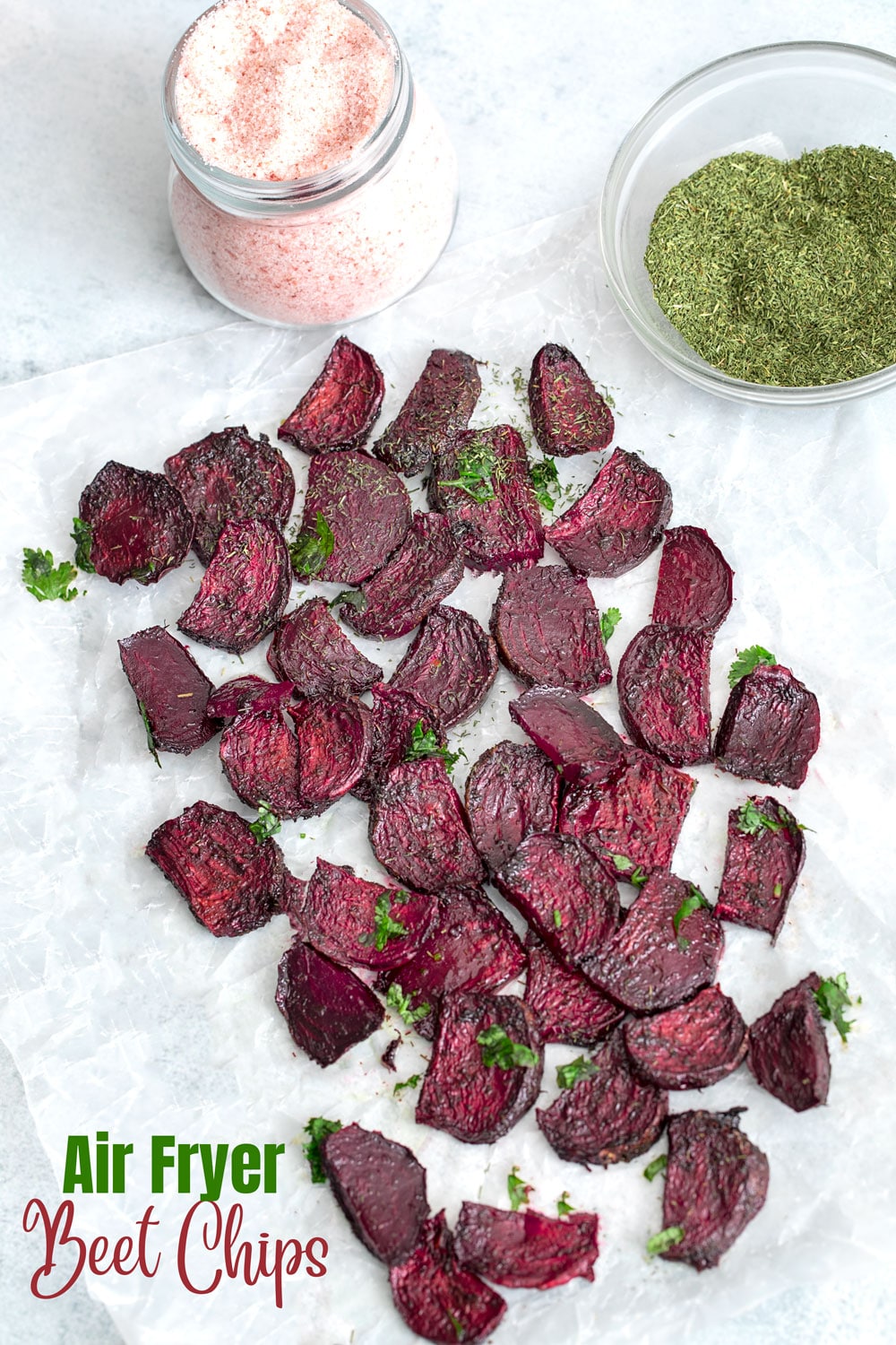 Top view of beet chips with salt bottle and dill seasoning in a bowl