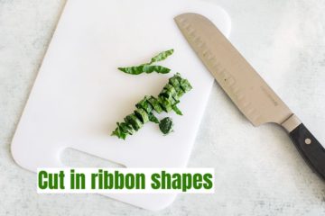 The leaves cut into chiffonade or ribbon-shaped on a white chopping board with a knife next to it.