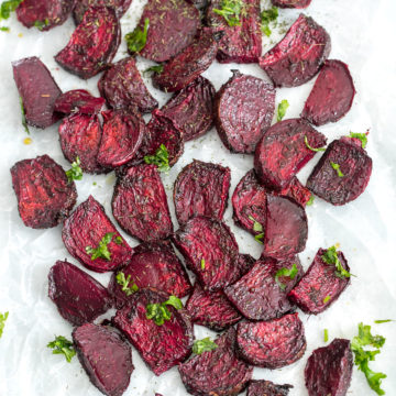 Top view of air fryer beet chips on a white wax paper with cilantro garnish
