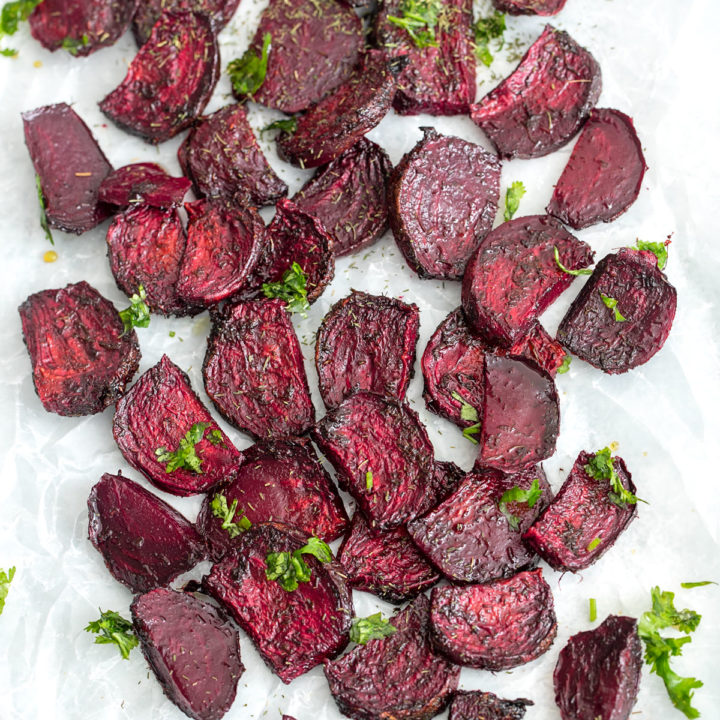 Top view of air fryer beet chips on a white wax paper with cilantro garnish