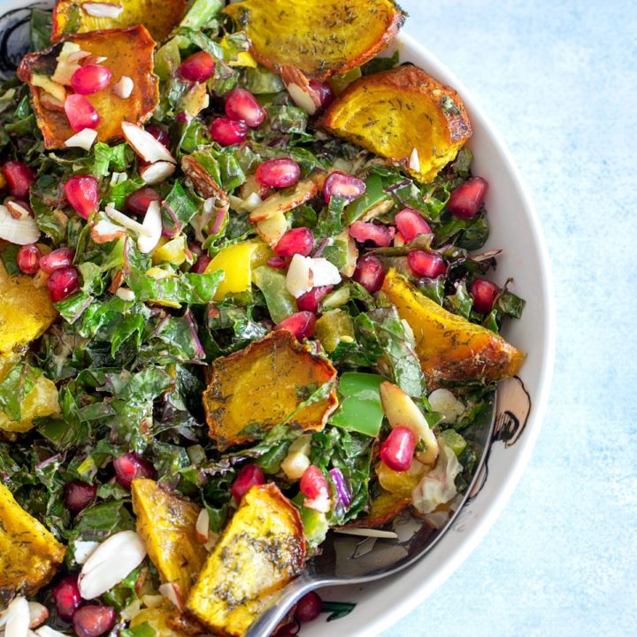 Top and closeup view of the warm kale salad in a bowl. Beet chips, pomegranate and almond slices are visible too