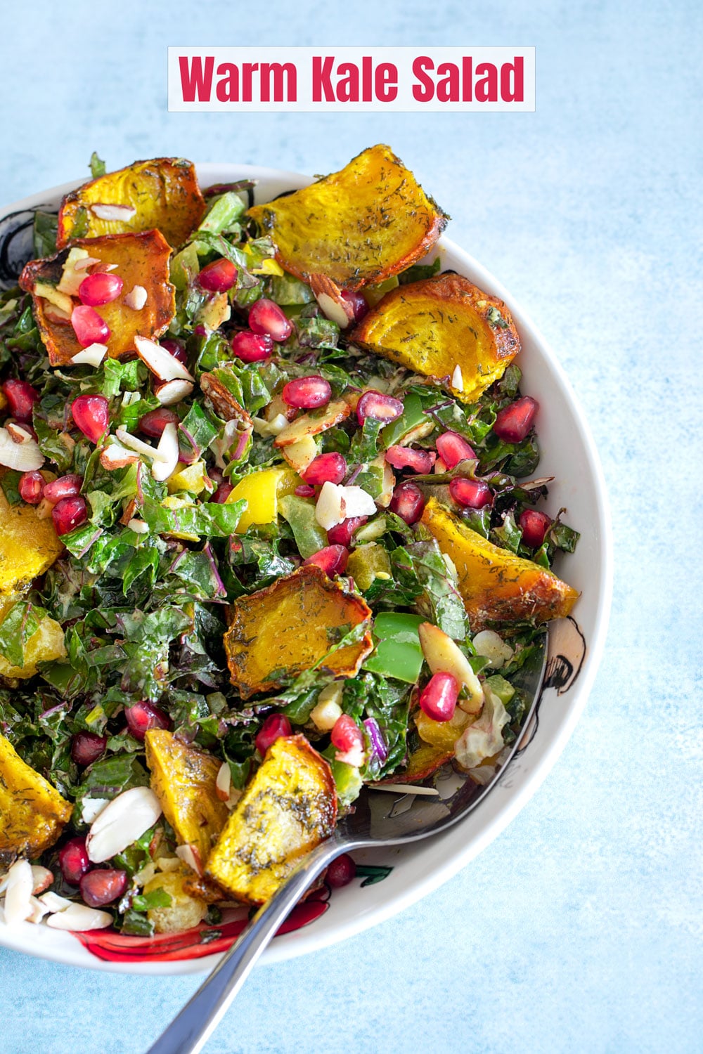 Top and closeup view of the warm kale salad in a bowl. Beet chips, pomegranate and almond slices are visible too