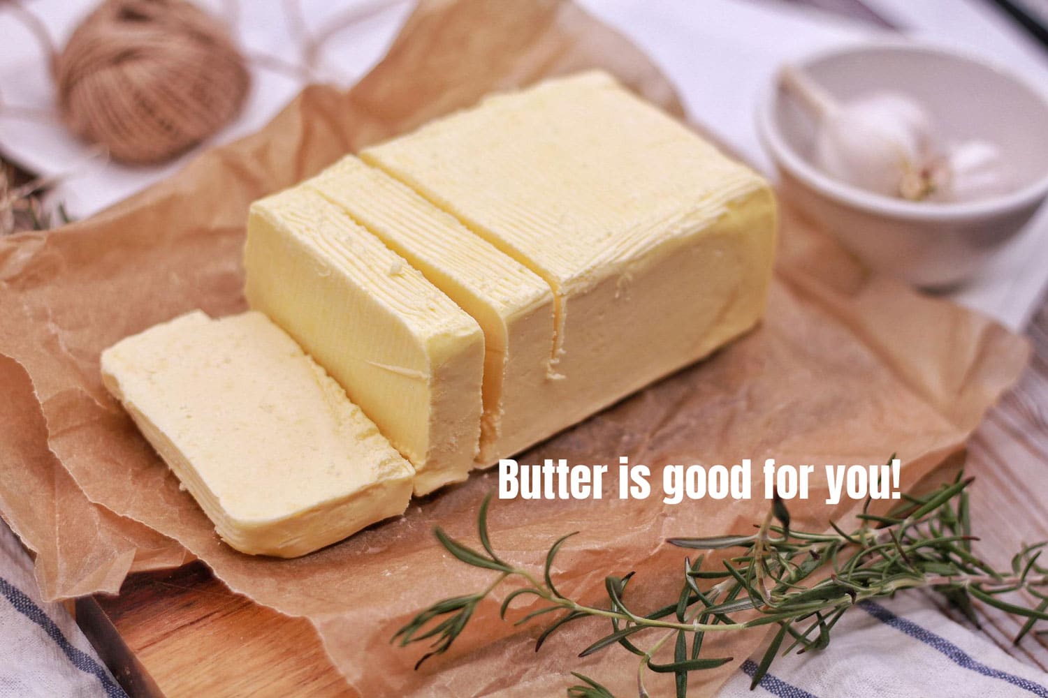 Angle view of a grass fed butter log partially cut into rectangle squares and placed on brown paper