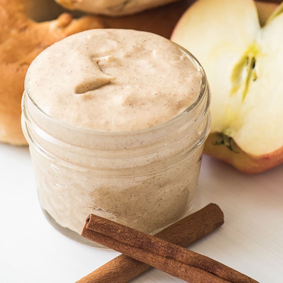 Front view of a silky brown butter in a mason jar with 2 cinnamon sticks on the side