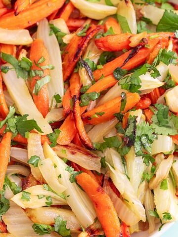 Top view of a bowl filled with carrots and fennel with cilantro garnish