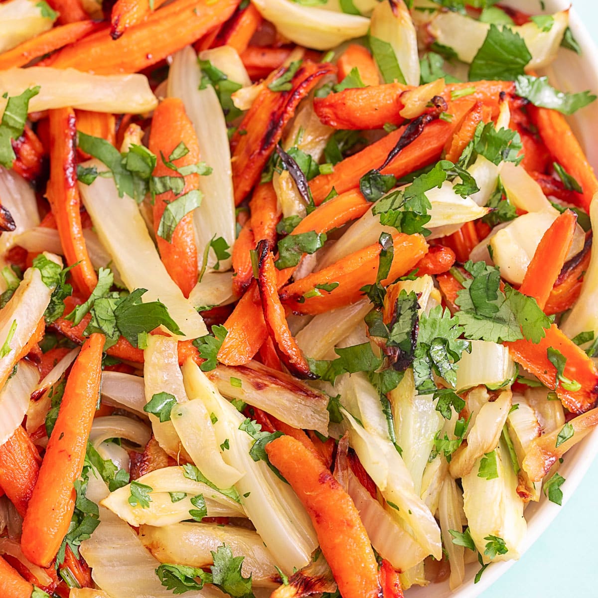 Top view of a bowl filled with carrots and fennel with cilantro garnish