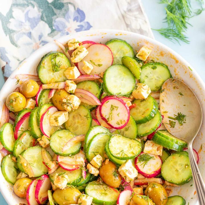 Top and closeup view of a spicy cucumber salad in a white bowl