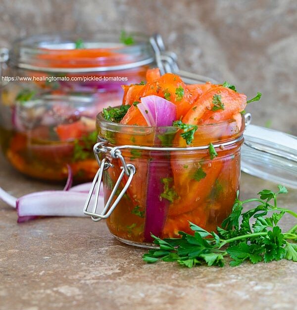 Front view of Pickled tomatoes in a mason jar and another jar in the background