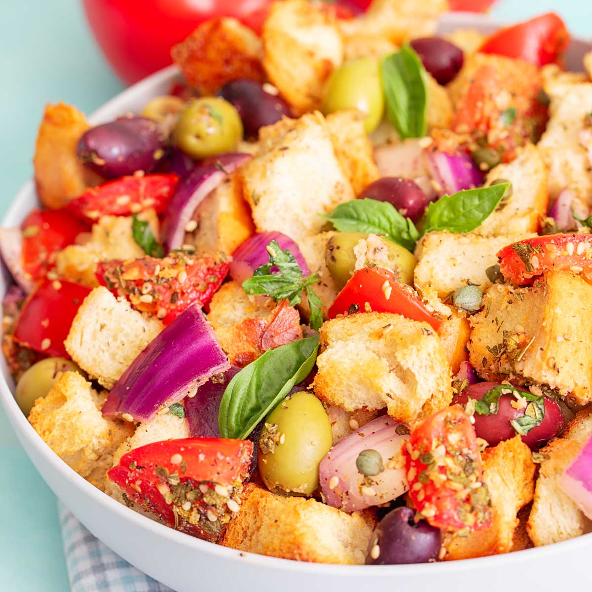 Front viewo of bread salad with olives, tomatoes, bread, onions and capers.