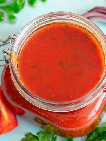 Top view and closeup of red enchilada sauce in a glass jar.