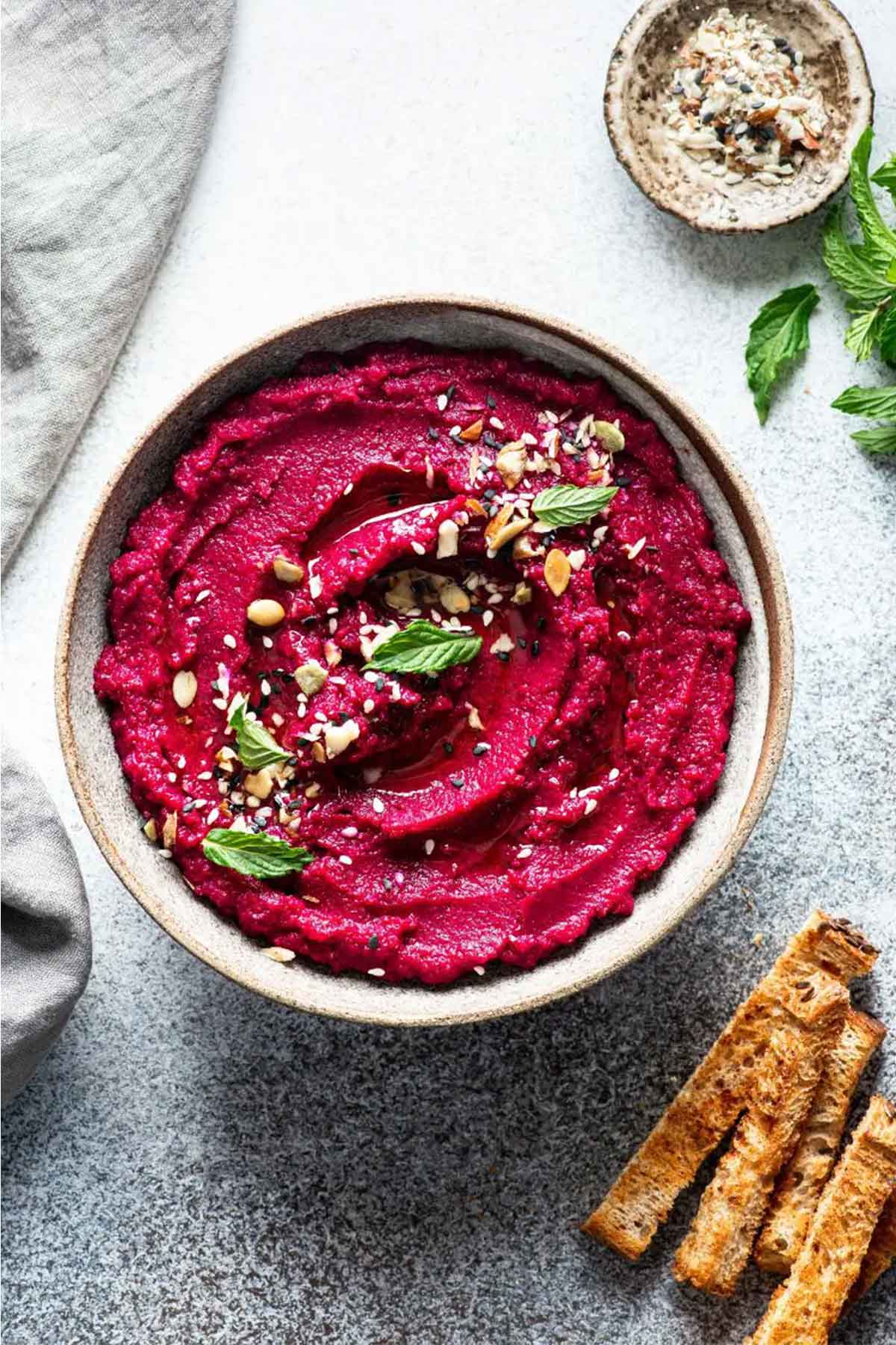 Top view of beet hummus in a white bowl.