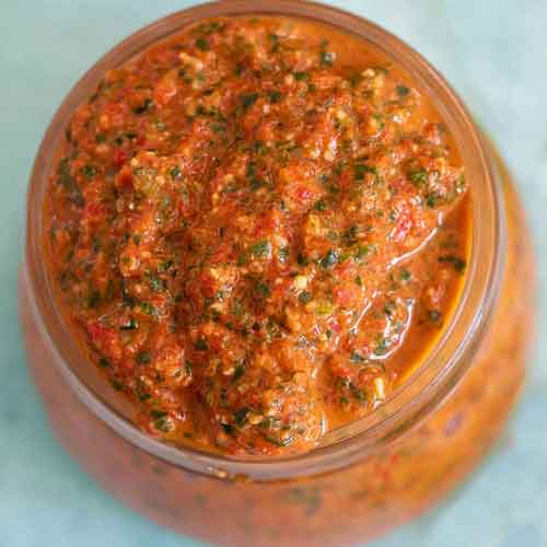 Top and closeup view of bell pepper pesto in a glass jar