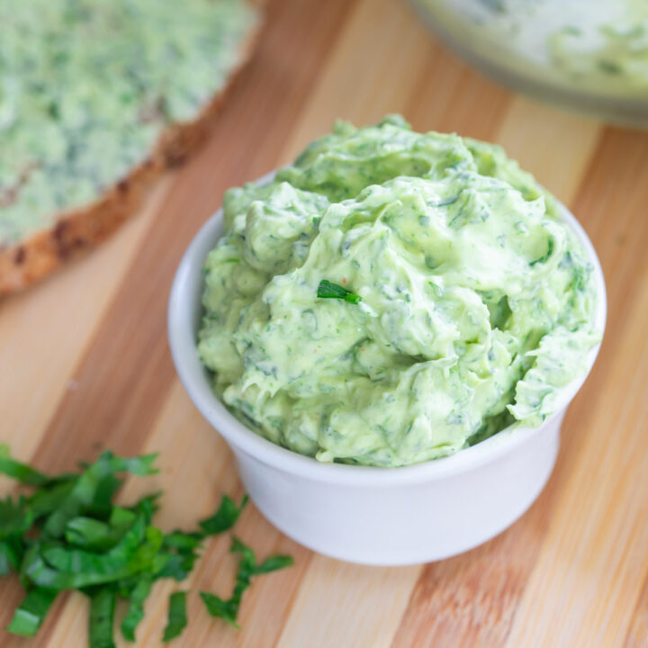 Angle view of scallion butter in a white ramekin.