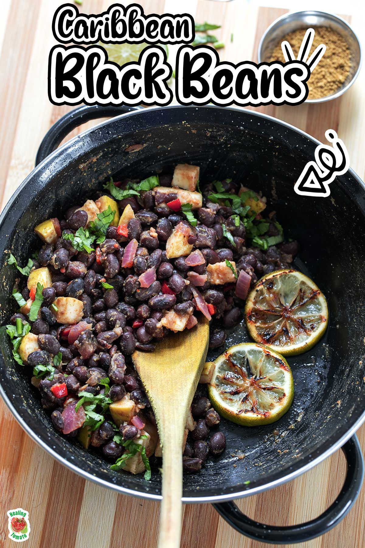 Top view of the beans in a black skillet. A wooden serving spoon is in it with a side of charred lime slices.