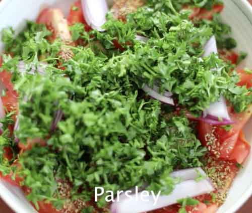 Top view of tomato wedges and red onion strips topped with parsley